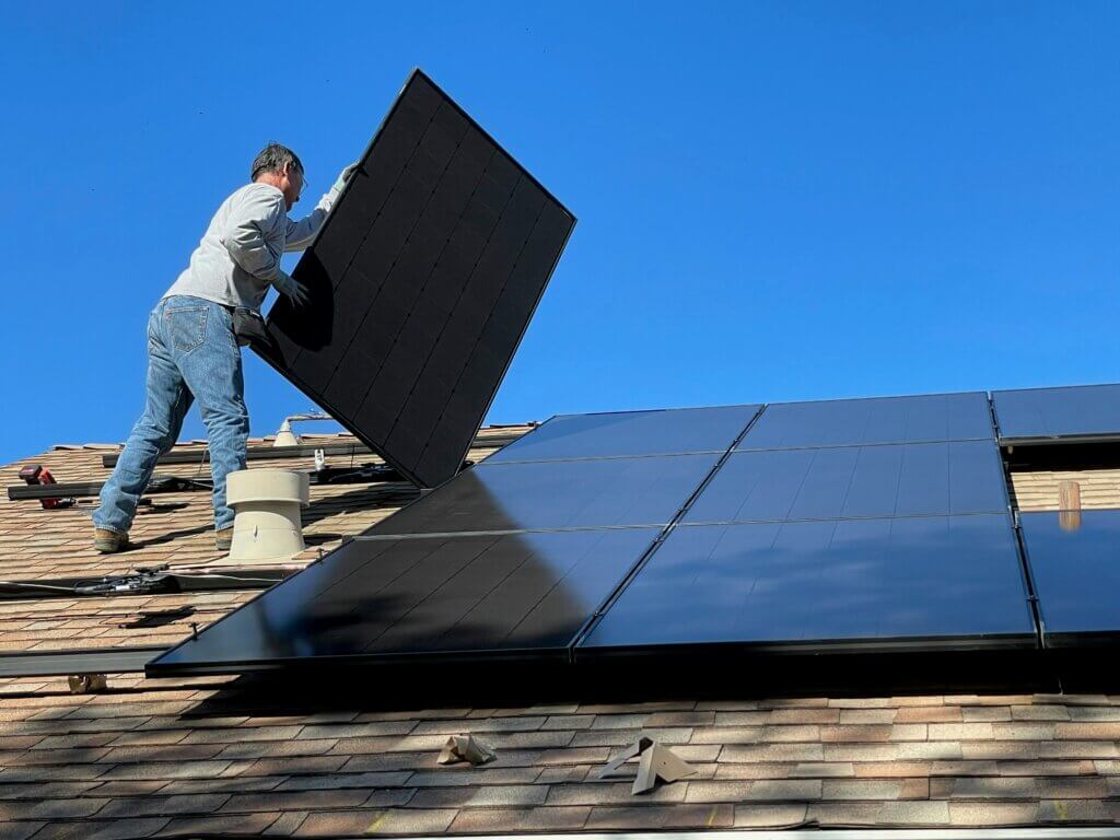 Technician installing a solar panel on a New Jersey home, illustrating solar financing options for residential systems.